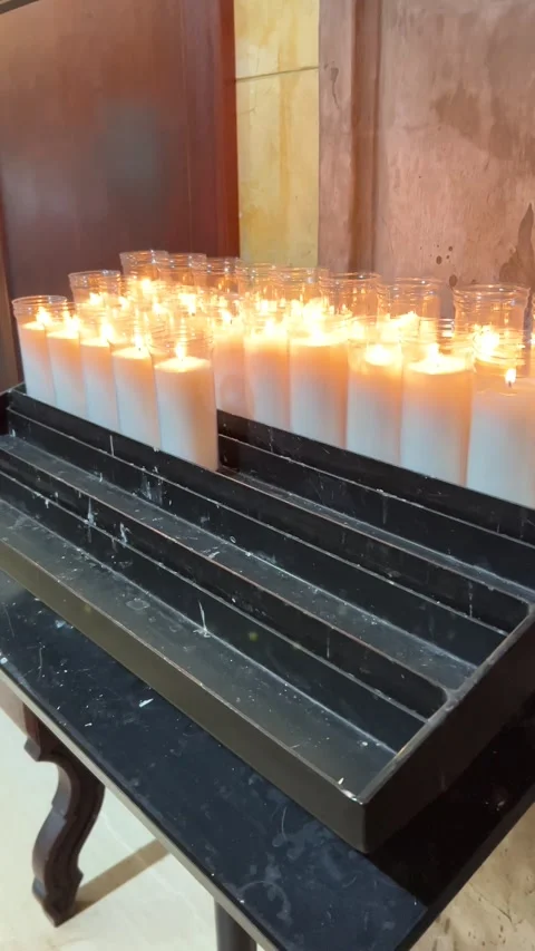 Row of white devotional candles burning in glass holders inside historic church Stock Footage 326465586