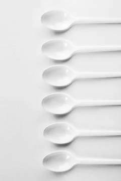Row of White Spoons on White Background Foto stock