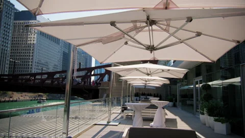 A row of white umbrellas are sitting on a patio next to a river Stock Footage 264254769