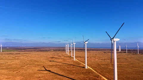 Row of wind turbines casting shadows on dry coastal steppe, Bulgaria Stock Footage 336728045