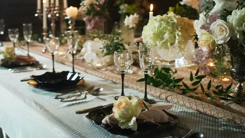 A row of wine glasses on a table served with black plates, candlesticks with Stock Footage 97719070