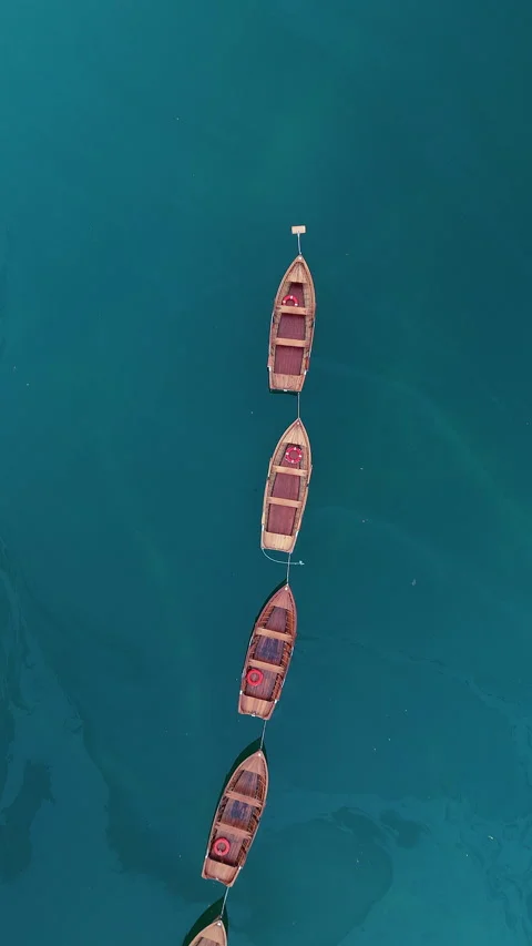 Rowboats Anchored in a Line Over Deep Blue Lake Waters Stock Footage 334773503