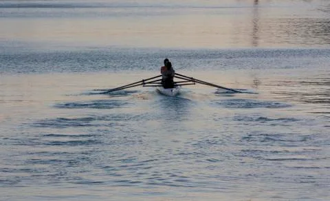 Rowers synchronously row the oars at sunset Stock Photos