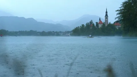 Rowers training on lake bled in the rain with island church in background. Stock Footage 330683535