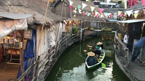 Rowing a boat between the houses in the floating village, evening vibe, 4K Stock Footage 223990579