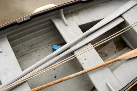 Rowing boat interior with rested oars. The boat is painted grey. Stock Photos