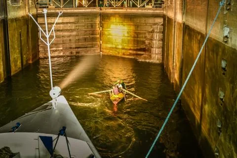 A rowing boat is in the lock of Esna in the light from a cruiser the lock of Stock Photos