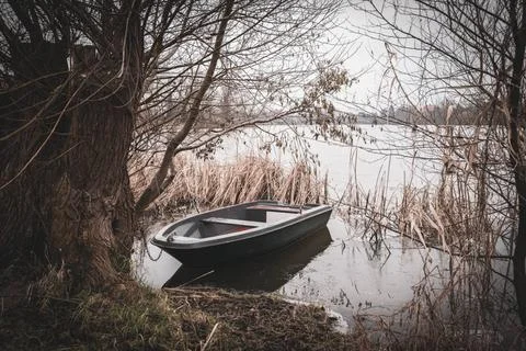 A rowing boat is moored on the shore of a frozen lake Stock Photos