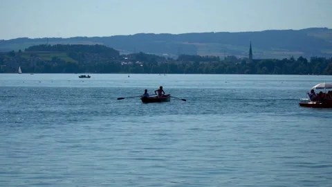 A rowing boat with two people on Lake Zug in Switzerland in summer sunshine. Video stock 313328232