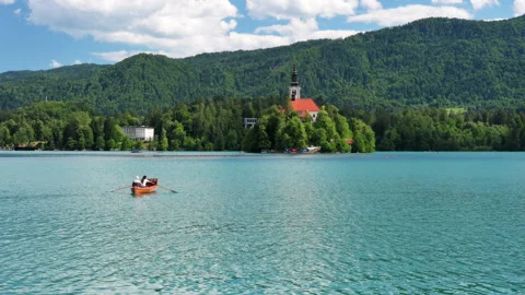 Rowing boat with two unrecognizable people crossing Lake Bled Stock Footage 340164789