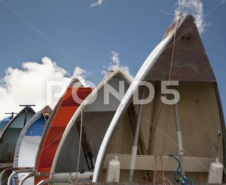 Rowing boats lined up vertically against blue sky Stock Photos