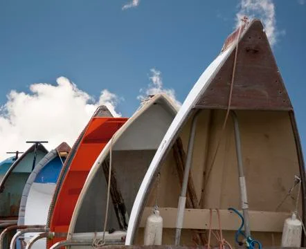 Rowing boats lined up vertically against blue sky Stock Photos