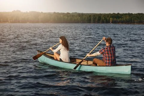 Rowing could also make for great exercise. a young couple rowing a boat out on Fotos Stock
