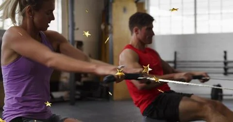Rowing pair pulling rowing handles in warehouse gym, wearing purple tank top and Stock Photos