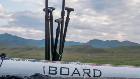 Rowing SUP board and oars against the backdrop of clouds and mountains Stock Footage 209796503