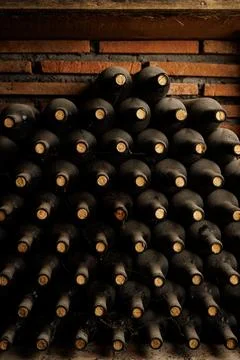 Rows of Aged Wine Bottles in a Rustic Cellar. Fotos de archivo