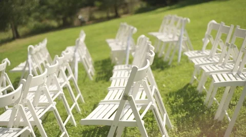 Rows of arranged white empty chairs on a green grass Stock Footage 67995341