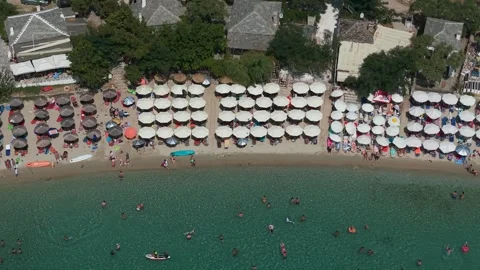 Rows of beach umbrellas, bathers and beach bars at Aliki, top down Stock-Footage 347176501