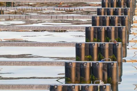 Rows of black floating dock pontoons with metal beams on calm water surface Stock Photos