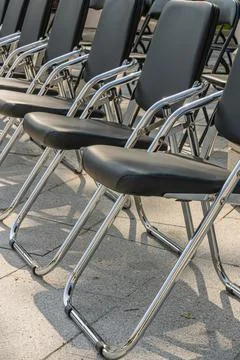 Rows of black folding chairs arranged outdoors for an event with geometric .. Foto stock