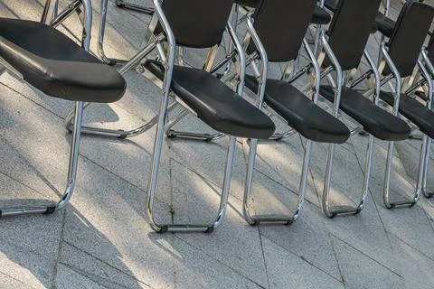 Rows of black folding chairs arranged outdoors for public event conference .. Stockfoto's