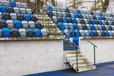 Rows of blue and grey numbered seats in a stadium near an aisle with concre.. Stock Photos
