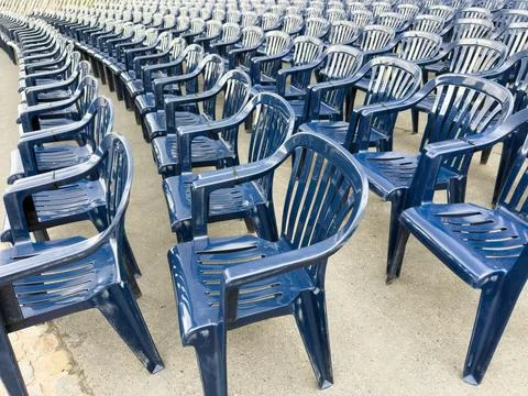 Rows of blue plastic chairs with backrests arranged in an organized seating.. Stock Photos