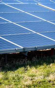 Rows of blue solar panels reflecting sunlight against a clear blue sky on a.. Stock Photos