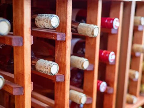 Rows of bottles of red and white wines on wooden wine rack Stock Photos