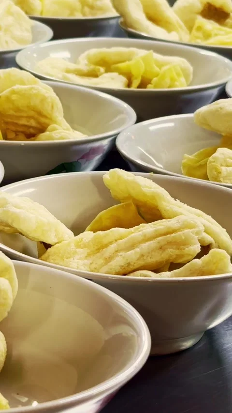 Rows of bowls contain assorted crispy fried crackers prepared for serving a.. Stock Footage 340115921