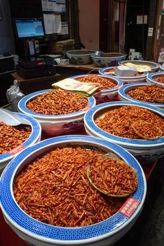 Rows of bowls hold dried, reddish-orange insect larvae Stock Photos