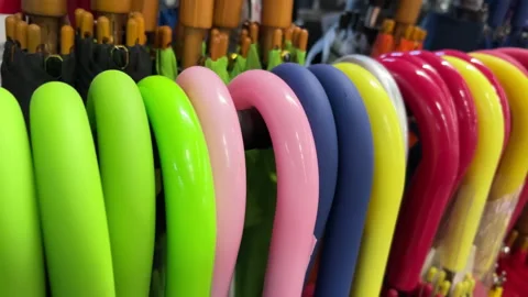 Rows of bright multi-colored umbrella handles hanging on a stand in a store. Stock Footage 200854552