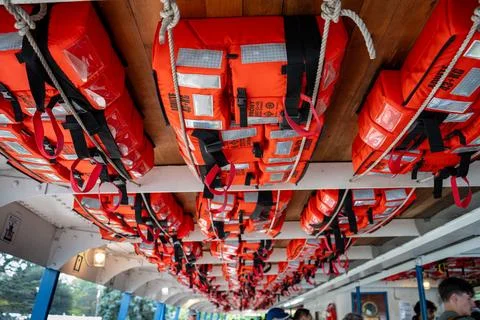 Rows of bright orange life vests hanging overhead, ready for water safety. Foto stock