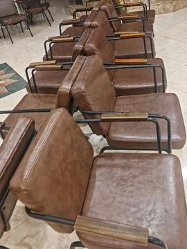 Rows of brown leather waiting room chairs in an indoor corridor Stock-Fotos