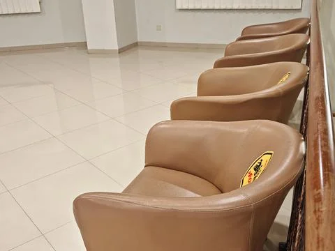 Rows of brown upholstered chairs in a clean indoor waiting area Stock-Fotos