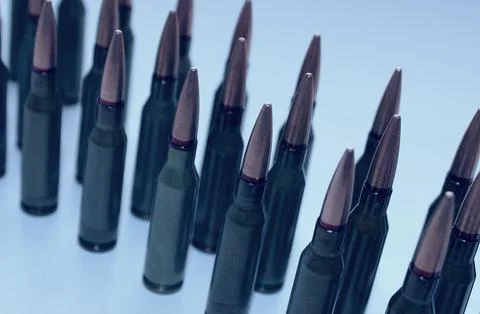 Rows of bullets for automatic rifle on a white glass surface Stock Photos