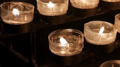 Rows of burning candles / tea lights close up in Cathedral Stock Footage 94868604