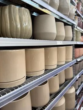 Rows of ceramic planters in various shapes are neatly arranged on store shelv Stock-Fotos