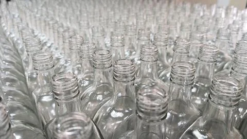 Rows of clear, empty glass bottles on an assembly line in a clean, modern f.. Stock Photos