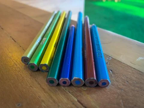Rows of colored pencils are placed on a wooden table (study table). Stock Photos