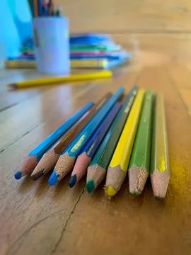 Rows of colored pencils are placed on a wooden table (study table). Foto stock