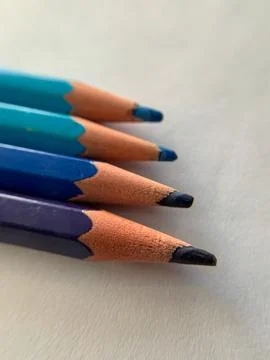 Rows of colored pencils (blue tone) are placed on a white paper Stock Photos