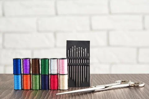 Rows of colorful threads, scissors and seamstress needles on the work table Stock Photos