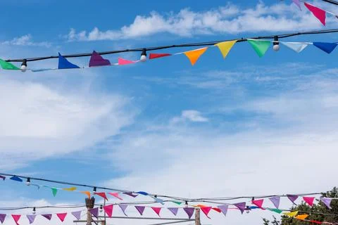 Rows of colorful triangular bunting flags hanging outdoors against a bright.. Stock Photos