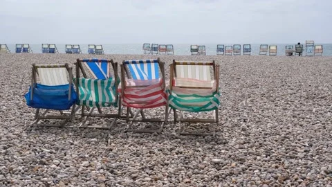 Rows of colourful empty deckchairs on pebble beach looking out to sea Stock Footage 195320885
