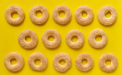 Rows of custard cookie rings on yellow background, top view, flat lay Stock Photos