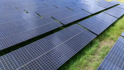 Rows Of Dark Solar Panels Generating Renewable Electricity In A Green Field.. Stock Photos