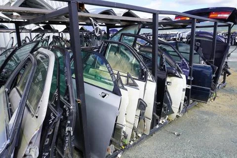 Rows of doors and trunk lids from cars on metal racks. Stock Photos