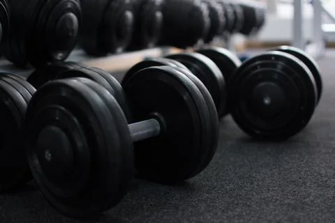 Rows of dumbbells in the gym in the dark colors. Stock Photos