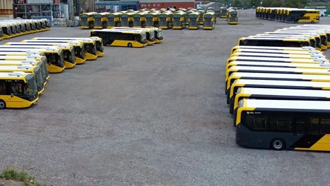 Rows of electric busses aerial view parked on industrial site low orbit right 库存影片 342403528